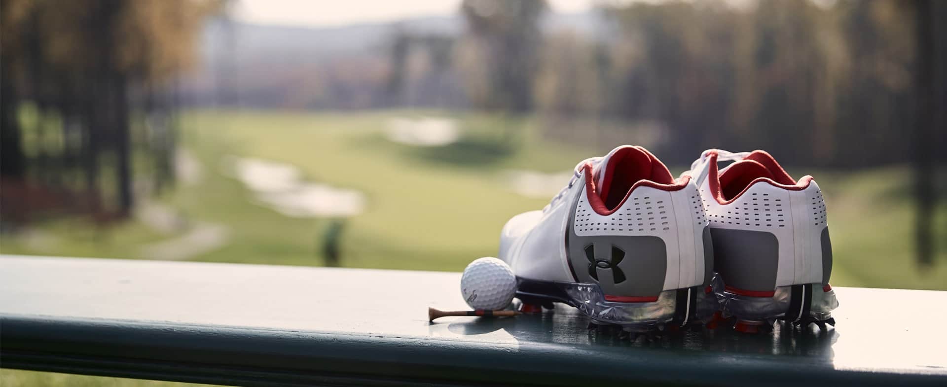 A wall with a pair of golf shoes with the Under Armour logo.