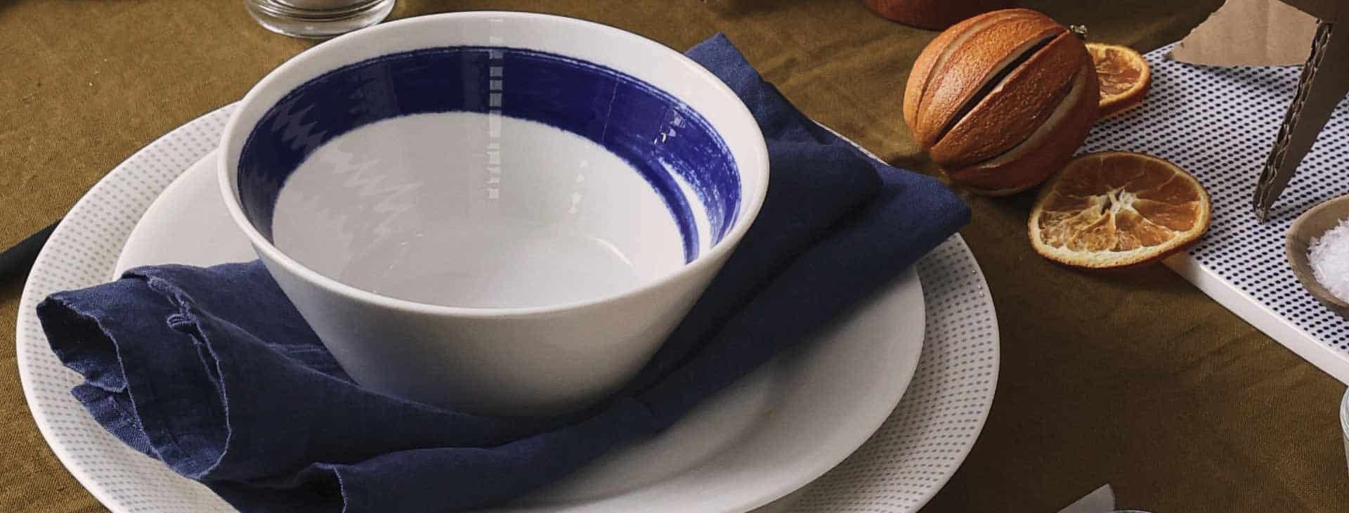 White and blue Royal Doulton crockery set out on wooden table.