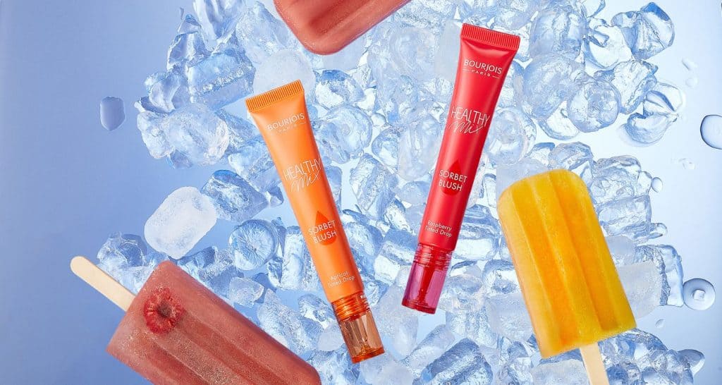 Image of tube lip gloss with fruity ice lollies on a background of ice.